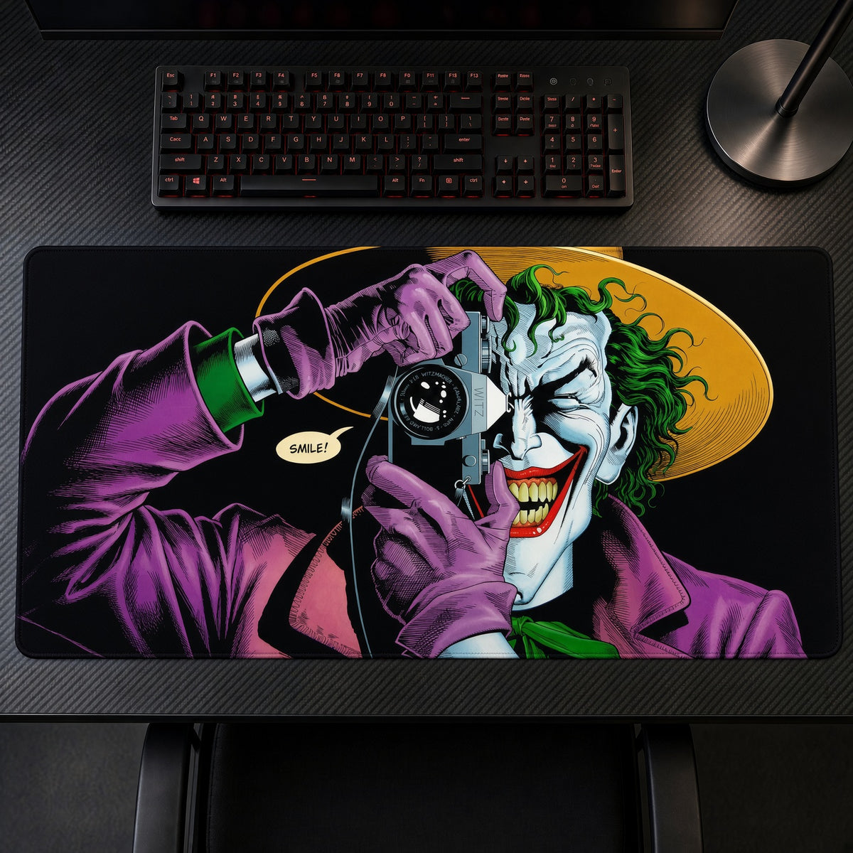 The Joker Camera Killing Joke DC Playmat on a gaming desk, top-down view