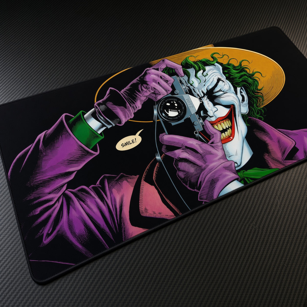 The Joker Camera Killing Joke DC Playmat at an angle on a gaming desk